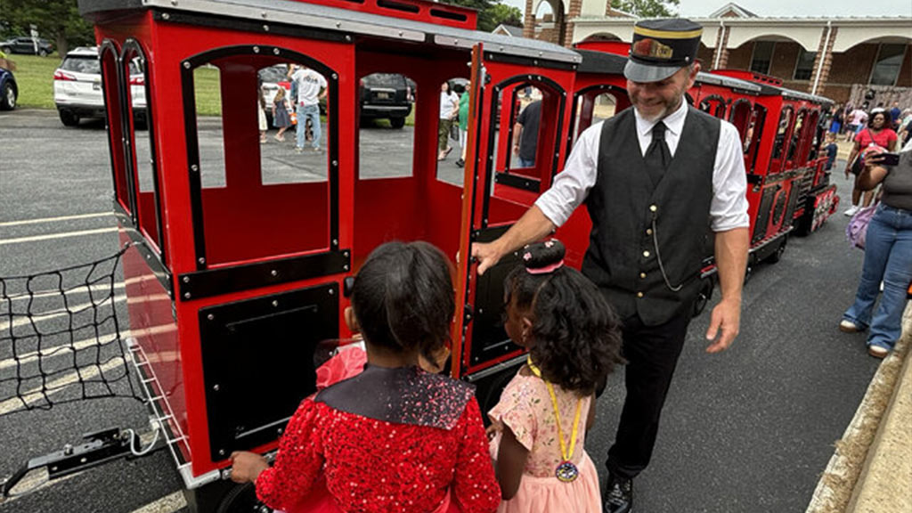 Attraction train rented for an outdoor family event, boarding area filled with excited children and parents