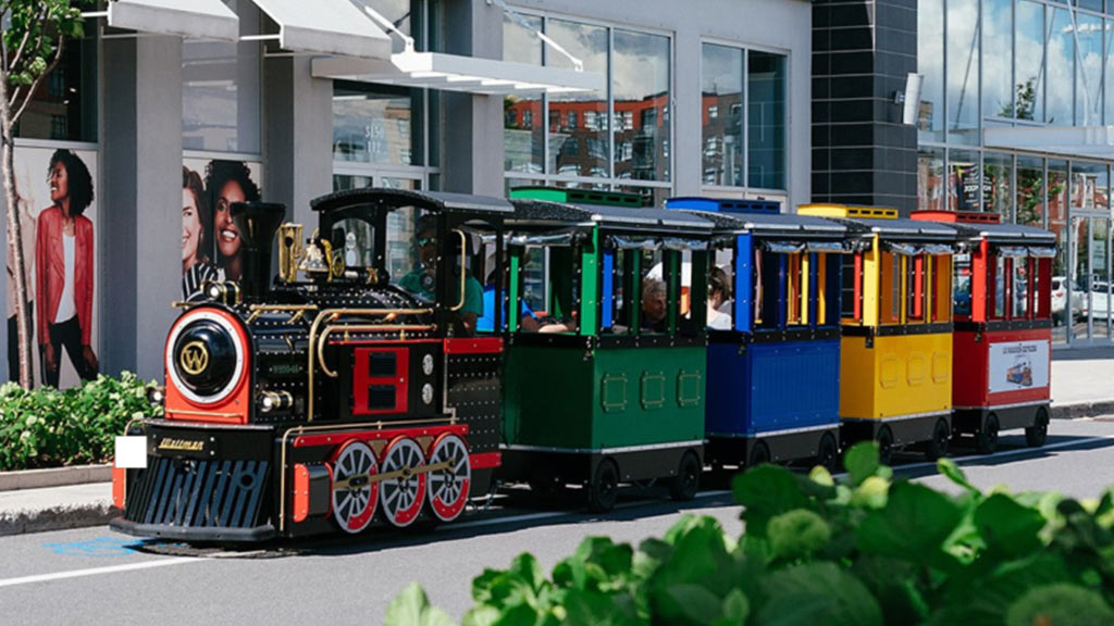 Mall train driving through a modern shopping mall with families and children on board