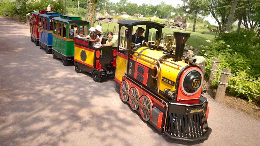 Mini Express trackless train carrying families through a zoo, improving visitor flow and providing memorable animal park rides